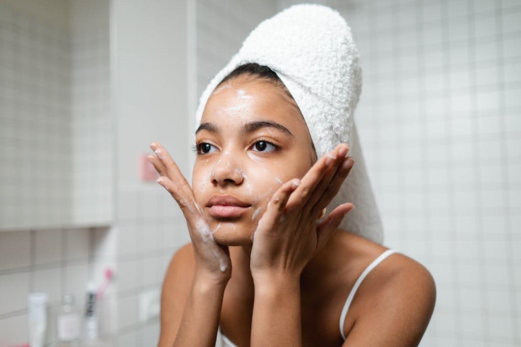 Mapeamento corporal Campinas: Entenda e Transforme seu Corpo Young woman practicing skincare routine with a towel wrap indoors.